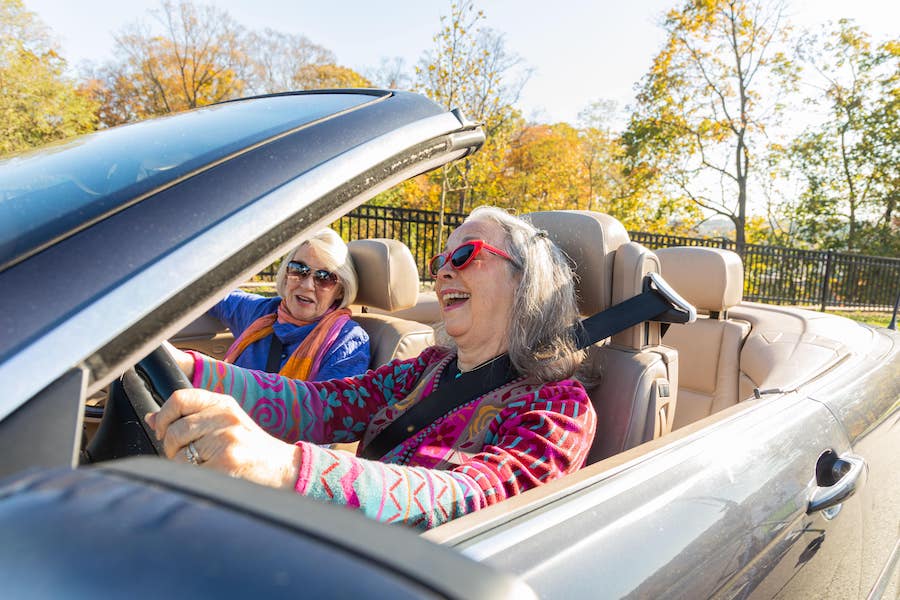 Two happy senior women driving a convertible 