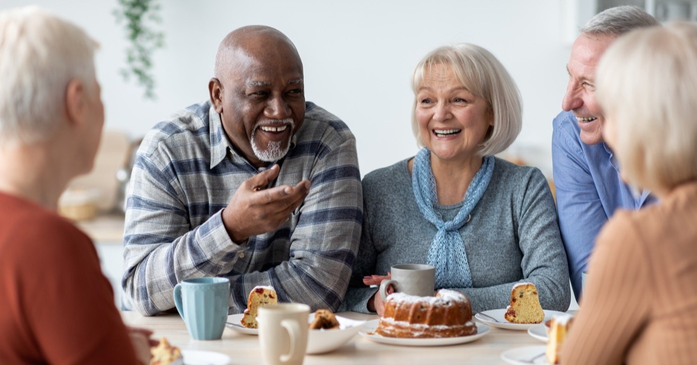 a group of 5 seniors sitting around a table laughing and enjoying breakfast.