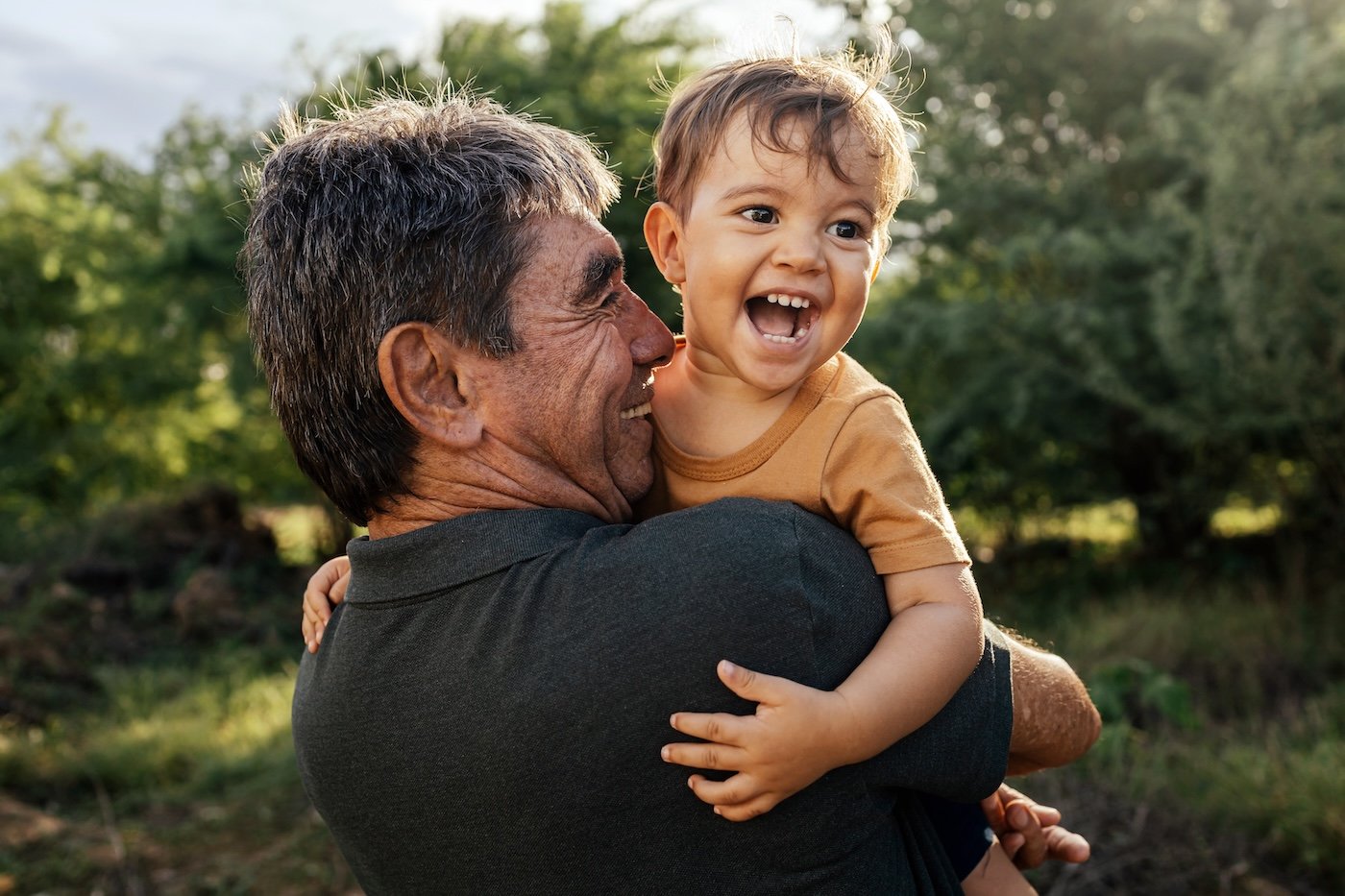 grandfather holding young grandson and laughing