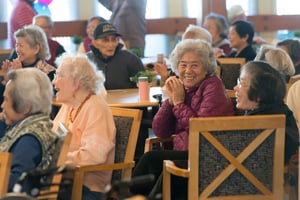 People sitting around tables clapping.