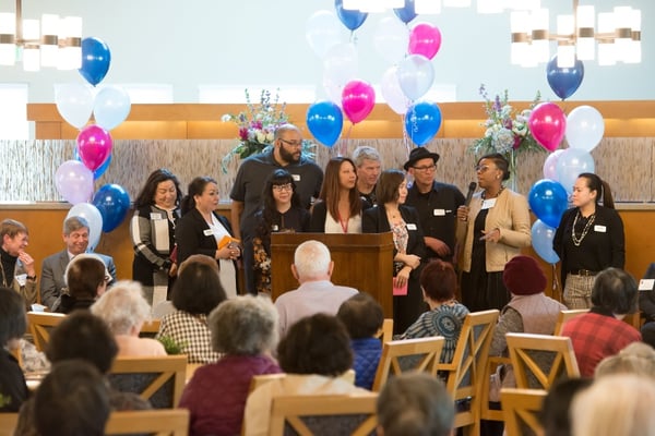 A group of people standing behind a podium with a microphone.