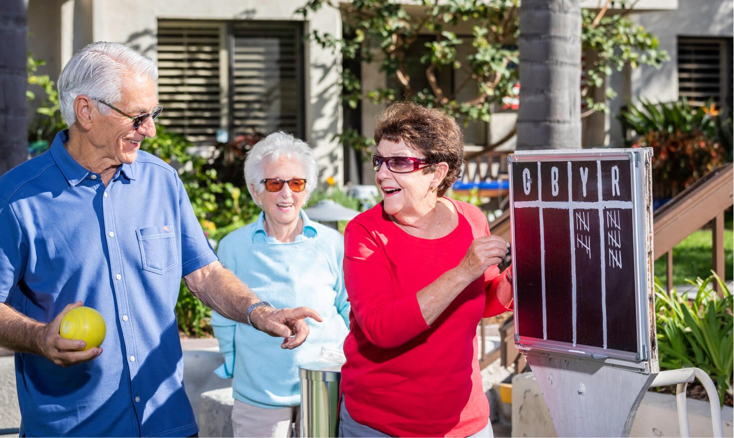 Three seniors playing lawn bowling outside at Regents Point