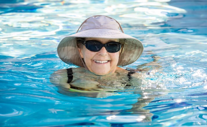 Senior woman in a hat and sunglasses in a pool
