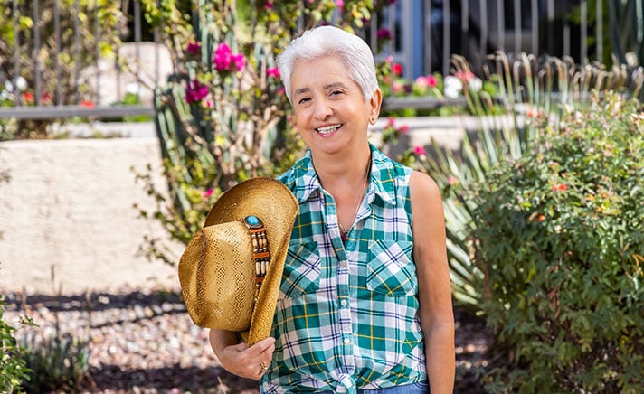 Senior woman holding a cowboy hat in the garden