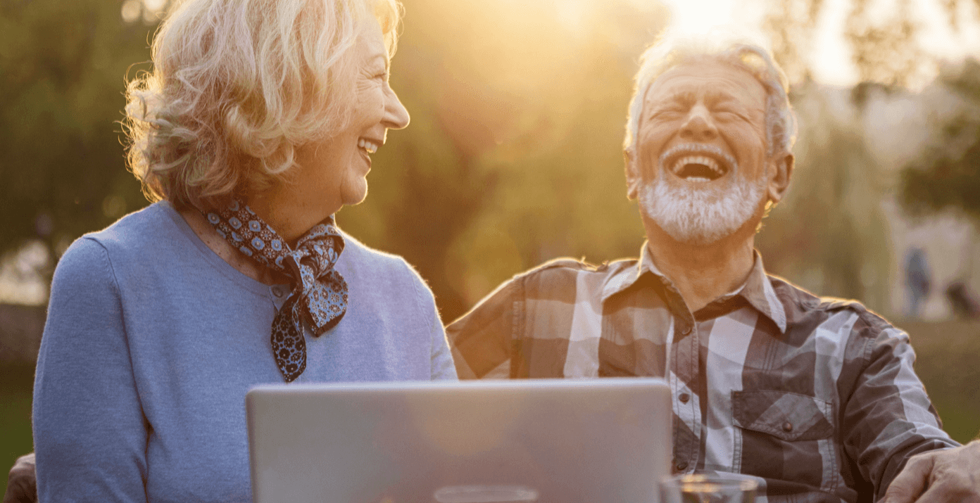 Older couple laughing in front of a laptop